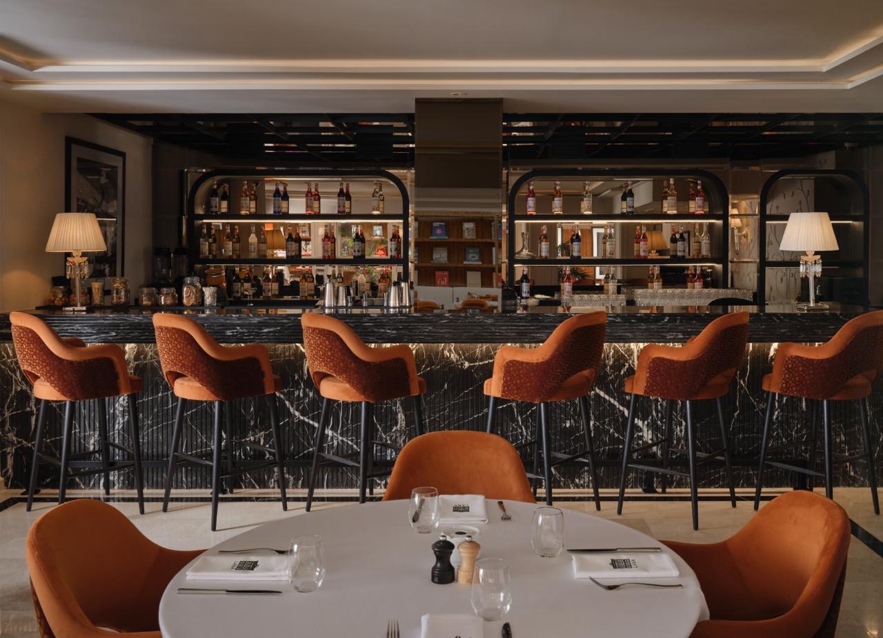 Le Bar Lana, comptoir de marbre noir, bouteilles éclairées et tabourets terracotta