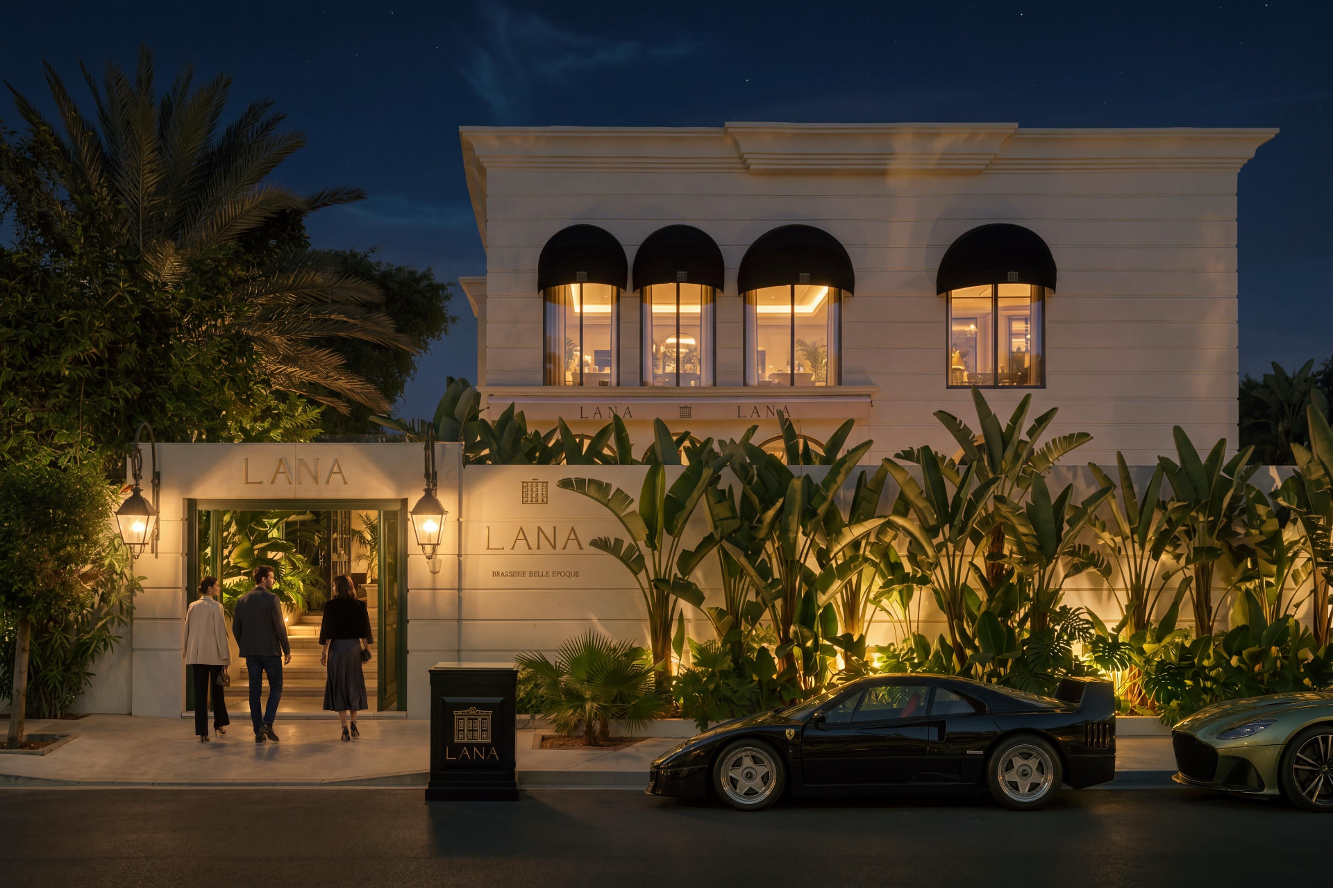 La façade de Lana, villa blanche illuminée à la nuit tombée, porte verte ouverte sur le hall